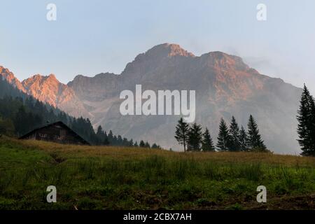 Sonnenuntergang in Österreich, Land Vorarlberg mit dem Widderstein im Hintergrund und einer Hütte im Vordergrund. Stockfoto