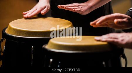 Trommel. Hände eines Musikers, der auf Bongs spielt. Der Musiker spielt den Bongo. Nahaufnahme der Musiker Hand spielen Bongos Schlagzeug. Afro Cuba, Rum, Schlagzeuger Stockfoto