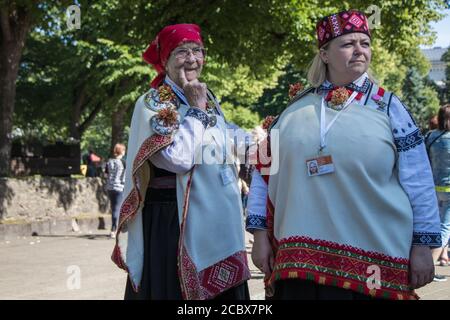 Eine ältere Frau und eine junge Frau in lettischer Nationalkleidung laufen in einem Stadtpark. Stockfoto