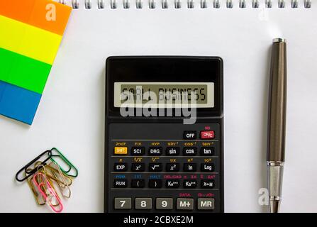 Taschenrechner mit Aufschrift "Small Business", weiße Notiz, farbiges Papier, Büroklammern, Stift. Geschäftskonzept. Stockfoto