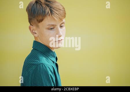 Ernst junger Mann in einem blauen Hemd auf einem gelben Hintergrund Stockfoto