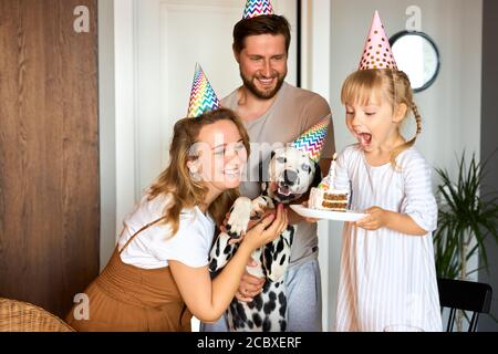 Tochter zu blasen, die Kerzen auf dem Kuchen, Geburtstagsfeier mit den Eltern zu Hause. Party-Konzept Stockfoto