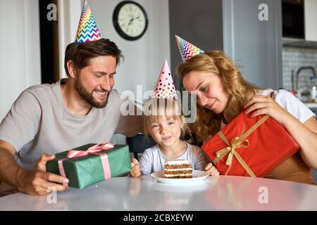 Glückliche Familie gratulieren Tochter Geburtstag in der Küche, geben sie Geschenke an sie, feiern. Familie zu Hause Stockfoto