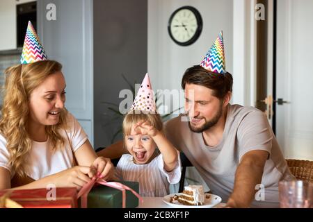 Glückliche Familie gratulieren Tochter Geburtstag in der Küche, geben sie Geschenke an sie, feiern. Familie zu Hause Stockfoto