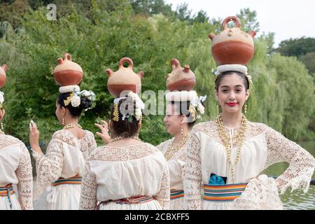 Eine Gruppe paraguayischer amerikanischer Volkstänzer, die kleine Zisternen auf ihren Köpfen balancieren. In Flushing, Queens, New York City. Stockfoto