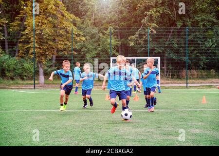 Kinder laufen und treten Fußballbälle auf Kinder Fußballtraining Sitzung Stockfoto