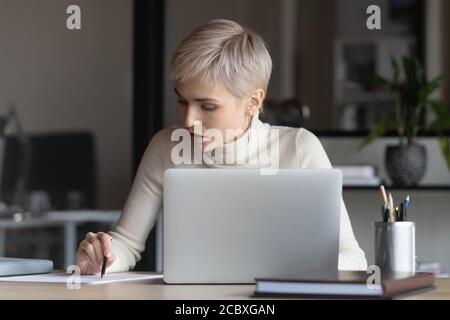 Fokussierte junge Geschäftsfrau lesen Vertragsbedingungen. Stockfoto