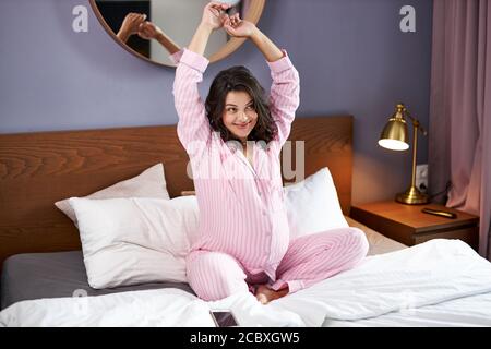 Süße lächelnde schwangere Frau strecken sich am Morgen, aufwachen, haben eine gute Laune. Zu Hause Stockfoto
