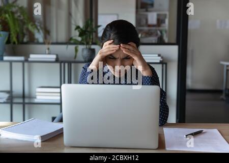 Gestresste junge indische Ethnizität Geschäftsfrau mit harter Aufgabe stecken. Stockfoto