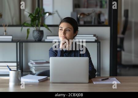 Verträumte nachdenkliche junge indische ethnische Geschäftsfrau, die an berufliche Herausforderungen denkt. Stockfoto