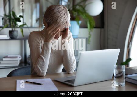 Gestresste junge kurzhaarige Geschäftsfrau, die unter Kopfschmerzen leidet. Stockfoto