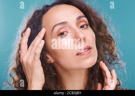 Junge wunderschöne Brünette Frau mit Unterauge Flecken berühren Tempel Stockfoto