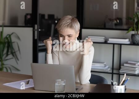 Glückliche junge blonde weibliche Führungskraft macht ja Geste. Stockfoto