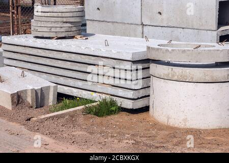 Stahlbetonplatten und Ringe für die Abwasseranlage auf der Baustelle. Industrielle Produktion von Zementprodukten. Stockfoto