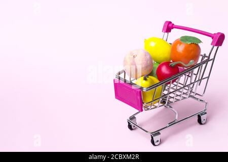Spielzeug Miniatur-Shopping-Trolley mit einem Sortiment von bunten übergroßen Obst und Gemüse Stockfoto
