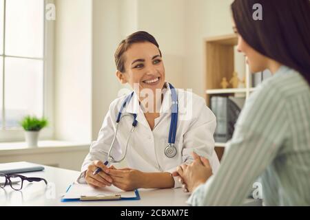 Junger Arzt im Gespräch mit Frau Patientin in der Klinik während des Besuchs Stockfoto