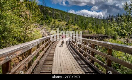 Radfahren über die hölzernen Trestle Bridges der verlassenen Kettle Valley Railway im Myra Canyon bei Kelowna, British Columbia, Kanada Stockfoto