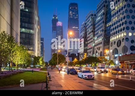 Straßenansicht von Peking, China, zeigt Verkehr, Fußgänger und moderne Bürogebäude in der Nacht in der Peking Central Business District. Stockfoto