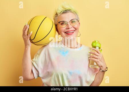 Glückliche reife Frau mit einer Pause während des Trainings. Nahaufnahme Porträt, isoliert gelben Hintergrund, Studio erschossen. Stockfoto