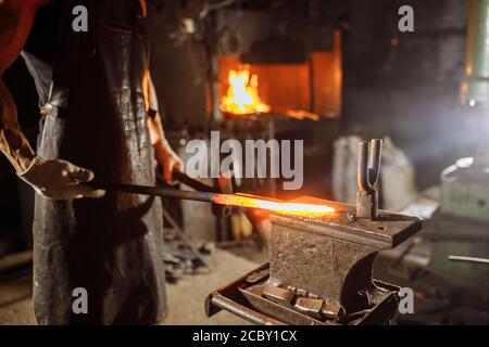Schmied Gestaltung rot heißen Metall isoliert in der Werkstatt, trägt Lederschürze und Handschuhe Stockfoto
