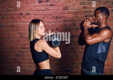 Fit muskulösen interracial paar Training mit Kettlebells Schaukeln in Cross fit Funktionstraining im Fitnessstudio. Stockfoto