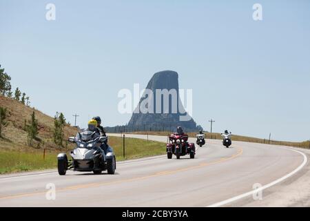 Motorradfahrer fahren am Freitag, den 14. August 2020, auf dem Highway 24 in der Nähe des Devils Tower von Wyoming. Jedes Jahr steigen Biker, die an der nahe gelegenen Sturgis Motorcycle Rally in South Dakota teilnehmen, auf das ikonische Wahrzeichen ab. Stockfoto