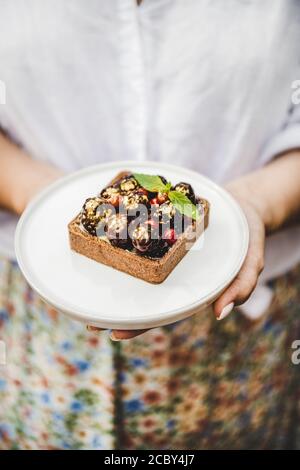 Kakao-Tartalette mit frischen Beeren der Saison in Frauenhand Stockfoto