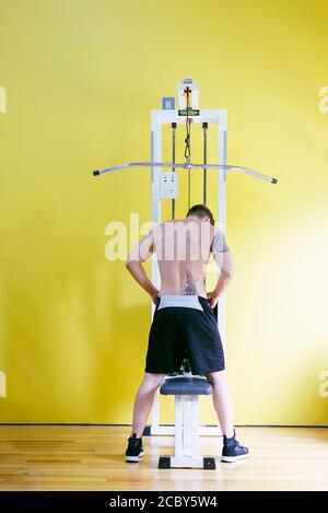 Fit Mann auf lat Pull-down-Maschine im Health Club. Trainieren Sie an der Pull-Down-Gewichtsmaschine Stockfoto