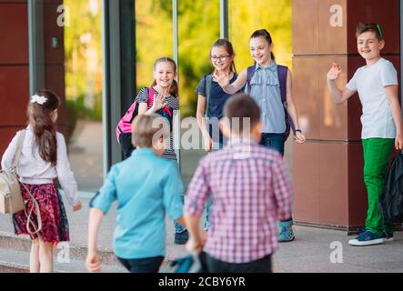 Mitschüler zur Schule gehen. Studenten begrüßen sich. Stockfoto