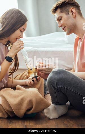 Junge kaukasische Paar, Mann und Frau genießen die Einnahme von Drogen zusammen zu Hause, sie entspannen auf dem Boden sitzen. Raucher verwenden Bong für die Herstellung von Cannabis. Hanf Stockfoto
