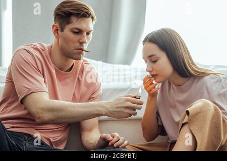 kaukasisches Paar fängt ein Buzz von der Verwendung von Cannabis, Marihuana. Mann und Frau genießen es, Drogen zusammen zu verwenden, sie wärmen Bong mit Cannabis und rauchen es. dru Stockfoto