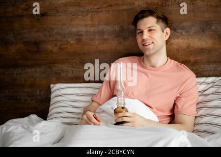 Junge kaukasische Mann raucht Cannabis, medizinisches Marihuana mit Bong, Legalisierung von Marihuana in der Welt, Drogenbehandlungskonzept. Mann leidet an Add Stockfoto