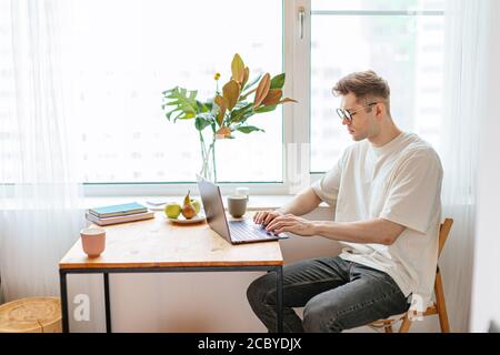 Technologie, Haus und Lifestyle-Konzept. Junge kaukasischen Kerl arbeitet mit Laptop zu Hause, er ist bei freiberuflicher Arbeit von zu Hause. Drinnen Stockfoto