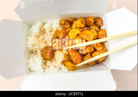 Chinesisches Essen Süße und saure, Orange oder Zitrone Huhn in einem Take Out Behälter mit Essstäbchen Stockfoto