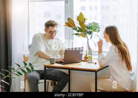 Familienkonzept. Schöne Dame Make-up am Morgen, während ihr Mann auf Laptop arbeiten, ist er bei Freiberufler. Jeder beschäftigt mit seinem eigenen Geschäft Stockfoto