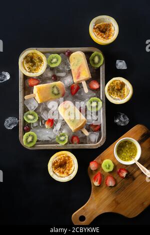 Hausgemachtes tropisches Eis oder Eiszapfen garniert mit Eisstücken und Kiwi, Passionsfrucht und Erdbeerscheiben, Draufsicht Stockfoto