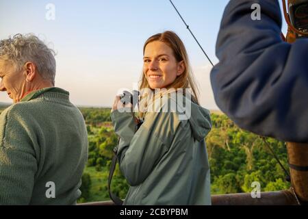 Touristen bereiten sich auf eine Fahrt im Heißluftballon bei Sonnenaufgang über die afrikanische Savanne in Kenia während einer Safari vor. Stockfoto
