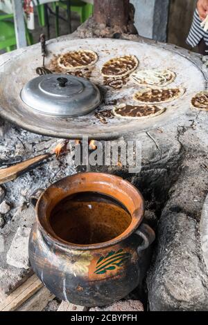 Erhitzen von Wasser in einem Keramiktopf über einem offenen Feuer in einem Restaurant am Straßenrand in Santa Maria Coyotepec in der Nähe von Oaxaca, Mexiko. Stockfoto