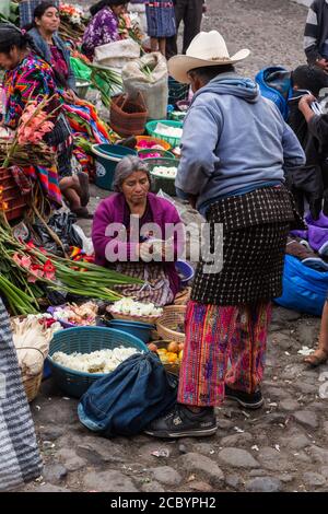 Eine Frau der Quiche Maya verkauft Blumen und Früchte auf dem Markt vor der Kirche Santo Tomas in Chichicastenango, Guatemala. Ihr Käufer ist ein Cakch Stockfoto