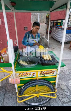 Ein Verkäufer, der Eloten und Ezitate auf der Straße im historischen Zentrum von Oaxaca, Mexiko verkauft. Elotes sind Mais auf dem Kob, die zuerst gekocht werden, dann Stockfoto