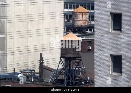 Wassertanks auf den Dächern eines alten Gebäudes zwischen Wolkenkratzern in Midtown, New York, NY, USA Stockfoto