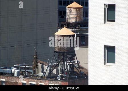 Wassertanks auf den Dächern eines alten Gebäudes zwischen Wolkenkratzern in Midtown, New York, NY, USA Stockfoto