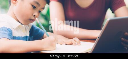 Sohn mit digitalen Tablet-Computer für das Studium und lernen, Internet online mit Mutter zusammen, Bildung von zu Hause, Familie Erholung, Mama lehren Junge ein Stockfoto