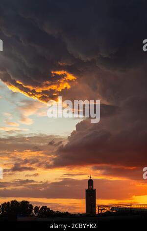 Fantastische leuchtend rote und bunte Sonnenuntergang über der Innenstadt Turm von Marrakesch. Erstaunliche Wolken und Sonnenlicht. Stockfoto