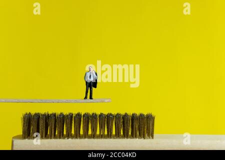 Miniatur Risikomanagement Geschäftskonzept - ein Geschäftsmann stehen Die Kante über den Nadeln Stockfoto