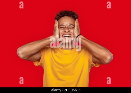 Freistil. Mulatto Sommersprossen Kerl in gelben T-Shirt stehend isoliert auf dunkelrosa Stockfoto