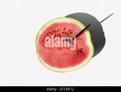 Ein Esslöffel in eine halb reife Wassermelone auf weißem Hintergrund eingefügt. Minimales sommerliches Fruchtkonzept. Stockfoto