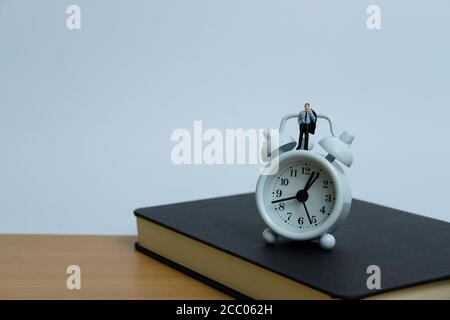 Miniatur Business-Konzept - ein Mann über Uhr und Notebook. Workload-Konzept Stockfoto