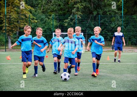 Kinder laufen und treten Fußball auf Kinder Fußballtraining Sitzung Stockfoto