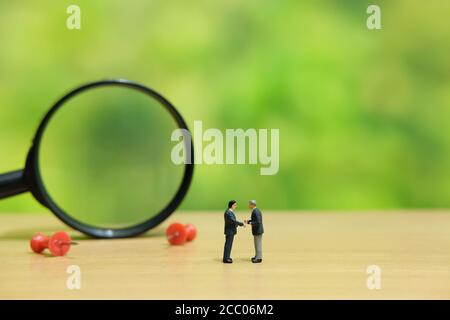 Business-Strategie konzeptionelle Foto - zwei Miniatur-Geschäftsleute machen ein Vertragsunterzeichnung auf dem Bürotisch Stockfoto